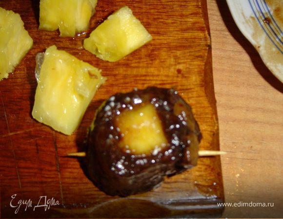 Очистите ананас от кожицы и нарежьте кубиками по 1 см. Оберните каждый кубик ананаса полоской мяса и скрепите зубочисткой. 