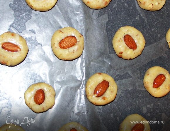 Тесто делим на 2 части.Каждую половину раскатываем в жгут и нарезаем на 20 частей.Формируем печенье.Выкладываем на противень с пекарской бумагой смазанной маслом.В серединку каждого вдавливаем миндаль обмазанный белком.Выпекаем при Т180С 20-25мин