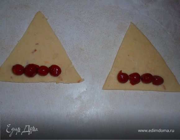 Вишню отправляем в дуршлаг. Тесто тонко раскатываем, нарезаем в виде треугольника укладываем вишню.
