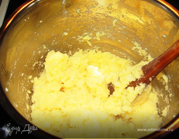 Снять с огня и медленно всыпать манку в молочно-сливочную смесь. Хорошо вымешать, дать минутку поварится, как масса станет однородной, снять с огня. Добавить два яйца и хорошо вымешать полученную массу, лучше всего деревянной лопаткой.