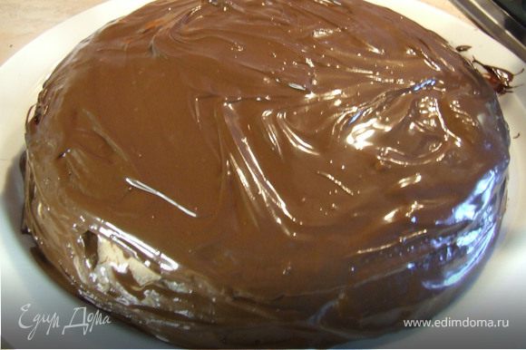Когда шоколад растопится, обмазать им поверхность и бока торта. Поставить торт в холодильник минимум на 3 ч. Посуду с остатками растопленного шоколада также поставить в холодильник. Когда шоколад застынет, соскрести его небольшим ножом. Украсить торт шоколадной стружкой.