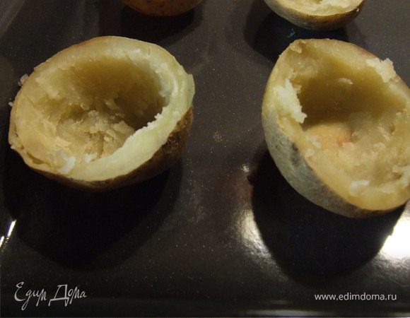 Картофель вымыть, почистить щеткой и уложить неочищенным на противень. Готовить при температуре 180-200С примерно 40-60 мин. в зависимости от величины картофеля. Готовность можно проверить вилкой - картошка должна стать мягкой. Разрезаем на 2 половинки и вынимаем серединку.