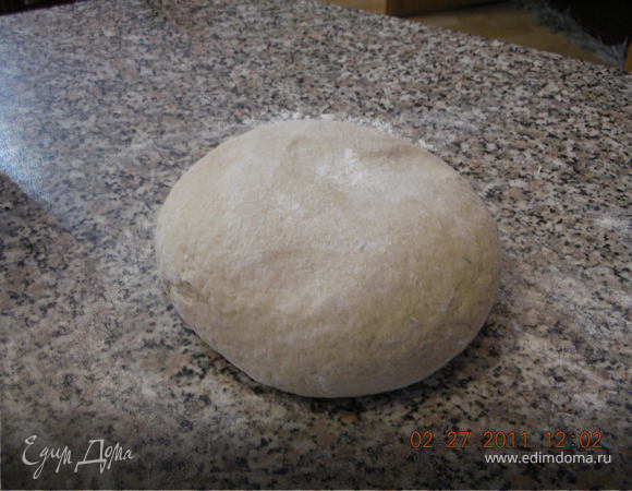 Когда тесто начнет отлипать от рук, стол присыпать мукой и сформировать шар. Перевернуть его "швом" вниз, уложить в миску, поставить в теплое место подниматься, прикрыв влажным полотенцем. Подъем теста может занять от 1 до 2 часов в зависимости от теплоты помещения.
