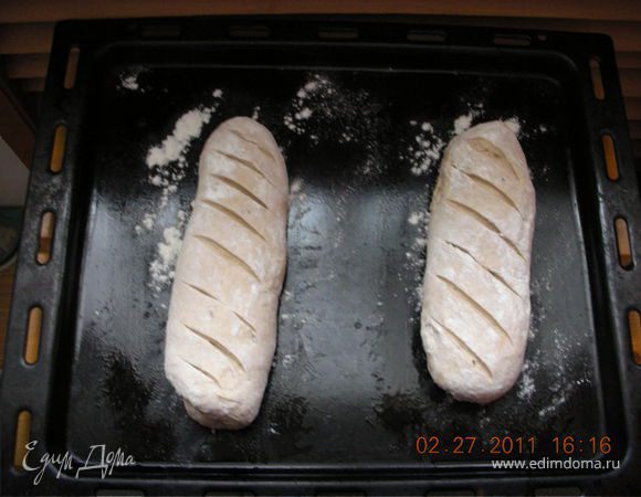 После того как тесто поднялось, нужно его разделить на две части и сформировать два батона (можно не делить и испечь круглую буханку), присыпать мукой, сделать острым ножом надрезы, уложить на присыпанный мукой противень и опять оставить в тепле на 1 час, прикрыв полотенцем. 