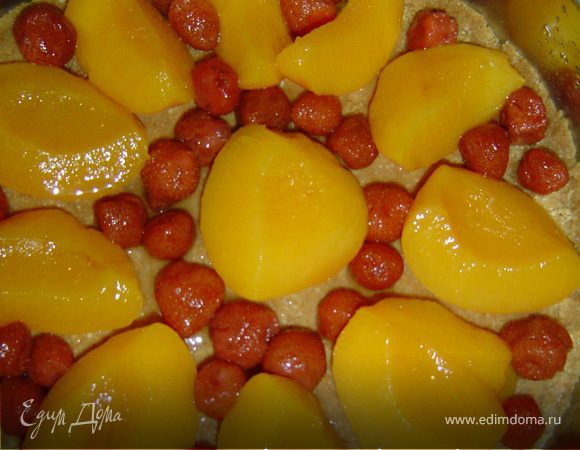 Достаем из холодильника форму с коржом и выкладываем на нее персики и смородину.