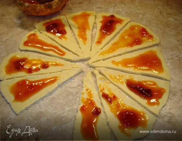 Тесто разделите на две части. Одну отложите в сторонку, накрыв тарелкой. Вторую раскатайте в круг толщиной около 7мм. Ножом по кругу нарежьте треугольники. На каждый положите начинку и сверните в рогалики, каждый из которых одной стороной обмакните в сахар.