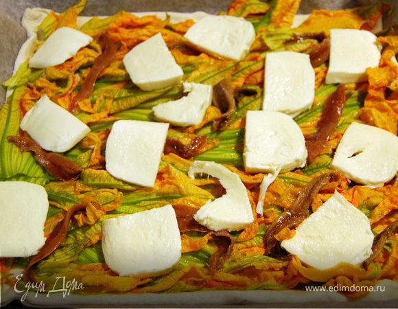 Порезать моцареллу на небольшие ломтики и уложить на пиццу, равномерно распределяя. 