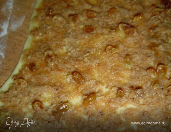 Раскатать первую половину в прямоугольный пласт,смазать его немного сливочным маслом,затем немного вареной сгущенкой,нанести половину яблочной начинки и изюм.