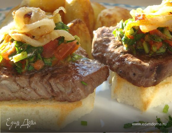 Собираем блюдо. Выкладываем крутоны, на каждый кладем по куску мяса, затем соус и сверху на него колечки жареного лука. На гарнир печеный картофель.