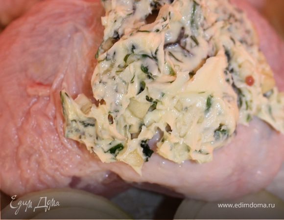 Аккуратно отделяем кожу от бедрышек и ложкой начиняем сливочно-пряным соусом. Сверху выкладываем остатки соуса. На противень выкладываем лук, нарезаный толстыми кольцами. На лук кладем куриные бедра. Посыпаем крупной солью. 