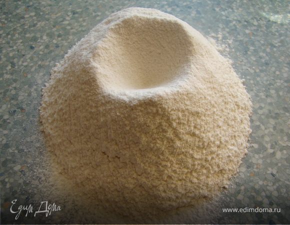 Делаем горку из муки, в средине делаем углубление и вбиваем туда яйцо, вливаем воду и добавляем соль. 