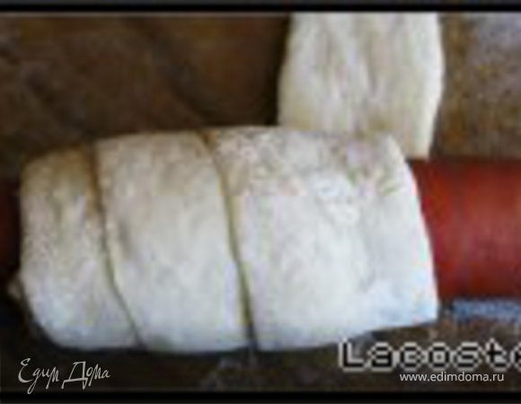 Сосиску кладем на полоску теста и по спирали оборачиваем.