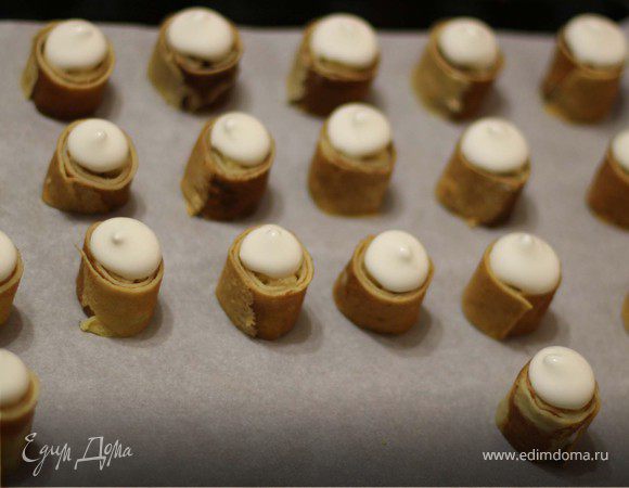 Белки взбить со щепоткой соли в пену. Добавить сахар, взбивать до устойчивых пиков. Белки переложить в кондитерский шприц (если шприца нет, можно выложить чайной ложкой), выложить на рулетики. Поставить в разогретую до 150 градусов духовку, запекать в течение 20-25 минут. 