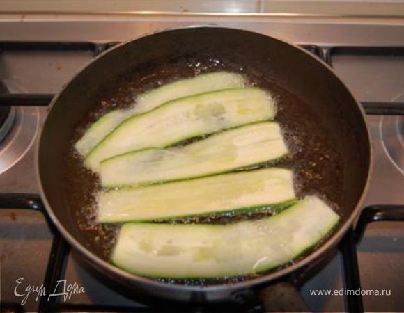 Цукини очистить, нарезать полосками и обжарить с обеих сторон. Выложить на бумажные полотенца, посолить, поперчить.