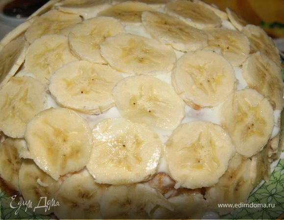 Продолжать выкладывать блины с начинкой пока не кончаться ингредиенты. Затем взять блин большого размера и накрыть им торт. Обильно смазать йогуртом и выложить бананы.