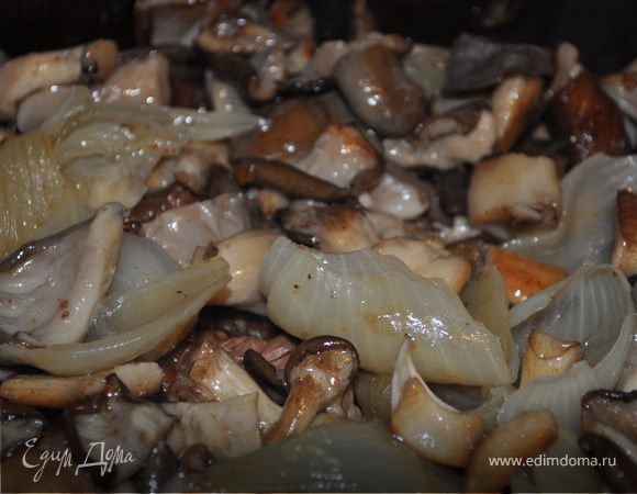 Достаньте готовое мясо из духовки и слейте содержимое через сито в сотейник.
Положите мясо обратно в кассероль. Выложите сверху грибы и лук.