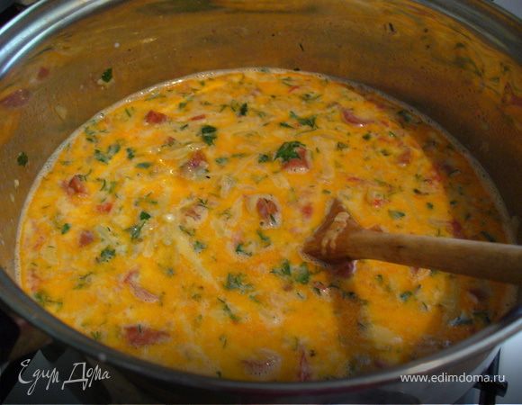 Туда же отправить колбаски, тушеные с зеленью томаты и еще раз перемешать.