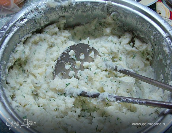 Когда картофель будет готов, слейте воду и помните картофель. Добавьте к нему творожную массу. Хорошо перемешайте. 