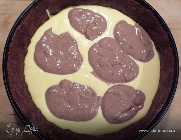 Разделяем тесто на 2 половины. В одну добавляем   через сито 2 ст.л. какао и шоколадную стружку. Вначале выкладываем в форму половину светлой массы, затем "лепешками"  половину темной, затем опять светлую, и снова темную. При  помощи ложки немного перемешать слои. 
Запечь в разогретой до 200°C  духовке на нижней полке в течение 40-45 минут.  Выключить духовку, открыть дверцу и оставить пирог еще на 30 минут. Затем достать, дать остыть. Тесто при помощи ножа отделить от краев формы. 
Лучше оставить пирог на ночь в холодильнике. 