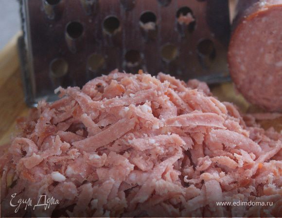 Натираем на крупной терке колбасу, отправляем в кастрюлю. Можно заменить колбасу на слабосоленую семгу, её необходимо мелко нарезать.