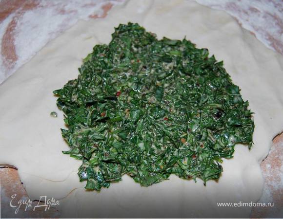 Немного раскатываем слоеное тесто и выкладываем на него зеленую добавку. Хорошо вымешиваем.