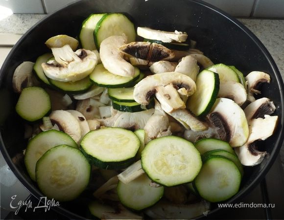 Добавить лук, грибы, цукини. Продолжить жарить при постоянном помешивании. 
