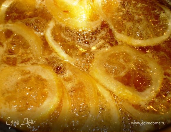 Лимончик, с которого мы частично сняли цедру, порезать тонкими кружками. Положить их в кастрюльку, добавить туда сахар,  масло, мед и воду. Довести до кипения, сделать на минимальный огонь и, периодически помешивая, карамелизировать 20 минут. По истечении времени кусочки лимона вынуть. Сок, образовавшийся при варке, охладить.