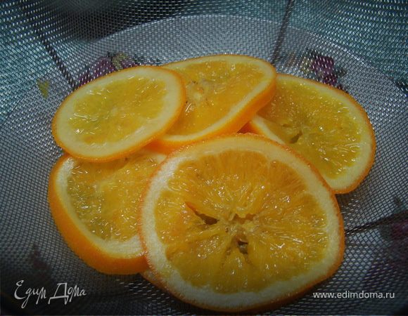 Затем, смешиваем воду с сахаром, ждем, пока полностью раствориться сахар и кладем туда наши апельсины. Варим где-то 1 час на маленьком огне, пока корка не станет прозрачной/полупрозрачной.
Достаем и снова даем стечь.  