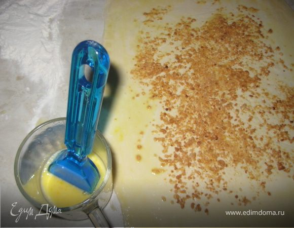 Лист слоеного теста раскатать по ширине и длинне примерно толщиной 2мм. Яйцо всбить в чашке с 1ст.ложкой холодной воды и смазать тесто полностью. Сверху посыпать орешками.