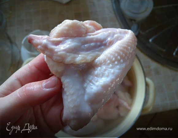 Крылышки залить холодной водой. Дать постоять минут 20. Слить воду, просушить кухонным бумажным полотенцем. Смазать соусом (маринадом). Время от времени мять руками, чтобы мариновалась она равномерно (так как закон всемирного притяжения все еще действует и соус стекает на дно посуды). Мариновать около 30 минут.