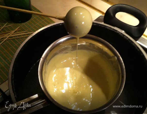 Растопить на водяной бане белый шоколад. Я приверженец натуральности, поэтому красители в шоколад не добавляла. Но можно сделать цветные шарики, добавив в шоколад пищевой краситель. Будет радужно и задорно. Достать шарики из холодильника, наколоть на шпажки, и аккуратно окунуть в белый шоколад. Поставить в стакан для застывания. Я для верности положила еще на 20 минут в холодильник:)