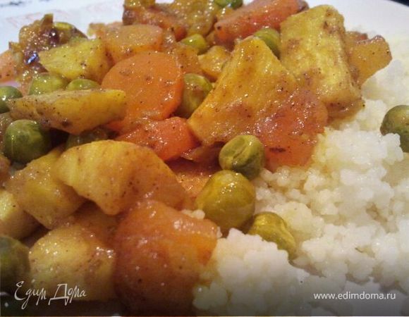 В глубокой сковороде разогреть оливковое масло и пожарить нарезанный полукольцами лук до мягкости. Нарезать овощи небольшими кусочками и добавить к луку. Всыпать специи и добавить соль по вкусу. Нарезать курагу и вместе с замороженным горошком добавить к овощам. Добавить 100-150 мл воды и довести до кипения. Затем уменьшить огонь, накрыть крышкой и оставить тушиться 15 минут. Тем временем в кастрюлю всыпать кускус, залить 200 мл кипящей воды и оставить для набухания. Когда овощи готовы, кускус распушить вилкой, посолить по вкусу и выложить на блюдо. Сверху выложить овощи. Можно украсить блюдо веточкой кинзы. 