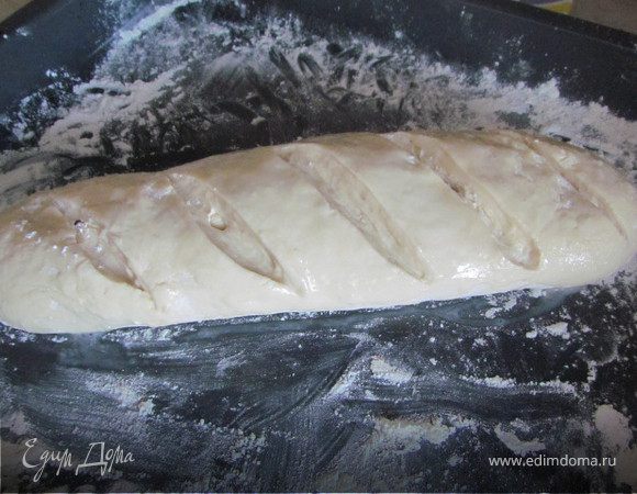 Делим тесто на 2 части и формируем наши багеты. Выкладываем багет на присыпаную мукой противень, делаем острым ножом насечки и смазываем яйцом. 