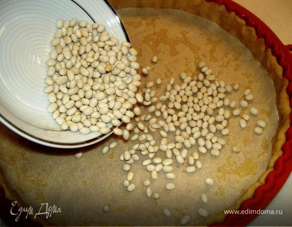 Прикрыть тесто пергаментом и насыпать сверху фасоль. Выпекать в разогретой до 200С 12 минут. Дать остыть основе, убрав фасоль. Убавить жар в духовке до 150С.