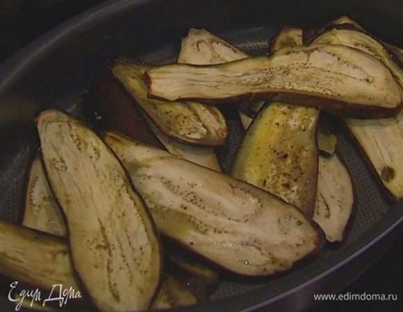 Баклажаны вымыть, нарезать вдоль длинными полосками, уложить в другой противень, посолить, поперчить, сбрызнуть оливковым маслом и поставить в духовку к перцу. Минут через 5 перевернуть баклажаны на другую сторону. Когда они станут мягче, прикрыть фольгой и допекать еще минут 10. 