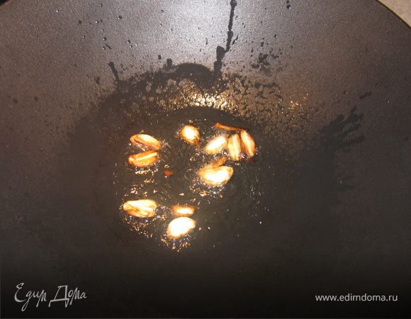 В воке разогреть масло и бросить туда половинки зубчиков чеснока. Готовить пару минут, пока чеснок не потемнеет