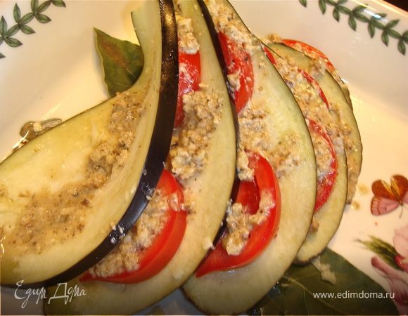 Духовку нагреть до 200С. Чеснок мелко измельчить и смешать с солью. Баклажан разрезать вдоль пополам. Каждую половинку разрезать на лепестки толщиной около 1 см, но не до конца. Должен получиться веер. Если вы все таки разрезали до конца, не огорчайтесь, достаточно просто скрепить лепестки зубочисткой. Каждый разрез смазать смесью чеснока и соли. 