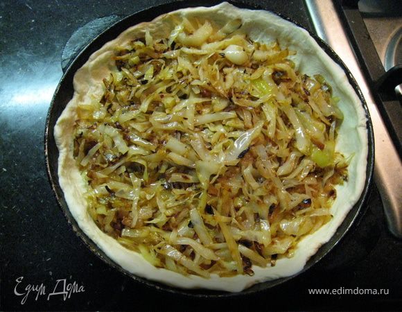 Оставить тесто при комнатной температуре. Выложить на сухую сковороду мелко нарезанный бекон, подождать пока подплавится. Добавить немного раст масла, выложить нашинкованную капусту, обжарить, посолить, поперчить. Раскатать тесто в два круга, выложить один на смазанный противень, затем капуста.