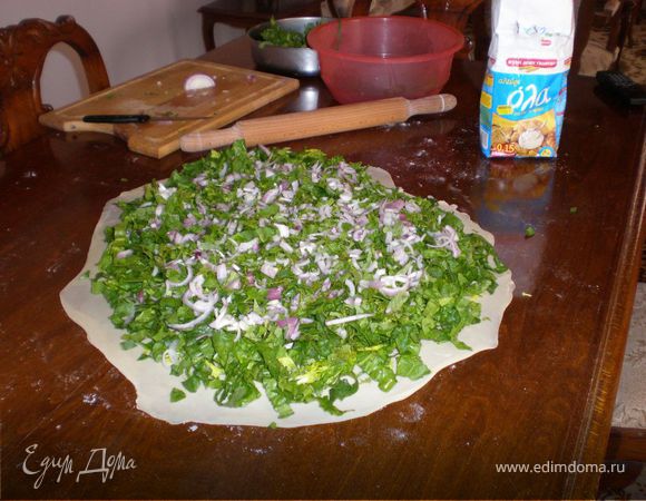 Сверху выложить зелень,а сверху зелени лук(я люблю много лука), Если желаете, поверх лука посыпаете пирог натертой фетой. Сверху посыпаете солью, как солите салат, например. И поливаете достаточно оливковым маслом.