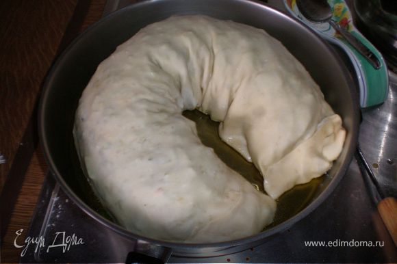 В большой сковороде разогреть оливковое масло (на умеренном огне, т.к.пирогу предстоит провести много времени на ней и если его положить на раскаленную сковороду - тесто быстро подгорит, а начинка останется сырой.)Масло должно быть достаточно. Выложить пирог на сковороду и на медленном огне жарить~30 минут с одной стороны (смотрите по цвету - зажаристый должен быть), перевернуть и жарить столько же с другой стороны.Смотрите чтобы масло немного шевелилось, шкварчало под питой,это правильная температура.