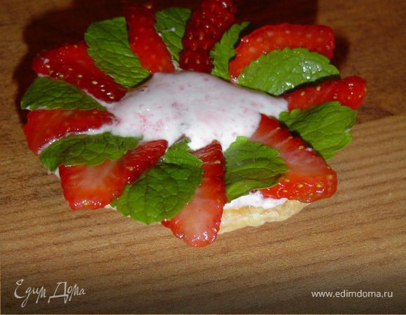 Выложите сверху клюквенного джема белковый крем в тарталетки.Нарежьте клубнику вдоль и уложите ее сверху крема, чередуя с листьями мяты.