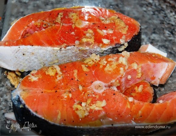 Форель помойте, очистите, разрежьте на 4 стейка. Чеснок пропустите через пресс, смешайте с тертым имбирем. Натрите маринадом стейки, положите в миску, посолите, поперчите и полейте оливковым маслом. Накройте пищевой пленкой и поставьте в холодильник на 40–60 минут.<br />
Маринад для форели должен быть легким, чтобы не перебить деликатный вкус рыбы. Перед запеканием в духовке стряхните частички имбиря, иначе он подгорит. 