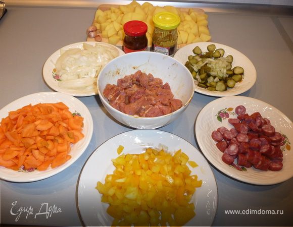 Мясо нарезаем порционными кусочками (2-3 см), маринуем в смеси горчицы (1 часть) и аджики (1/3 части). Немного солим, перчим. Оставляем минут на 20, пока подготавливаем остальные ингредиенты.
Морковь режем колечками, лук - полукольцами (лук немного обжарить на растительном масле), болгарский перец - небольшими полосочками, картошку - кубиками, колбаски и корнишоны - кружочками. Сельдерей тонкими ломтиками. Чеснок делим на зубчики, но не чистим.

