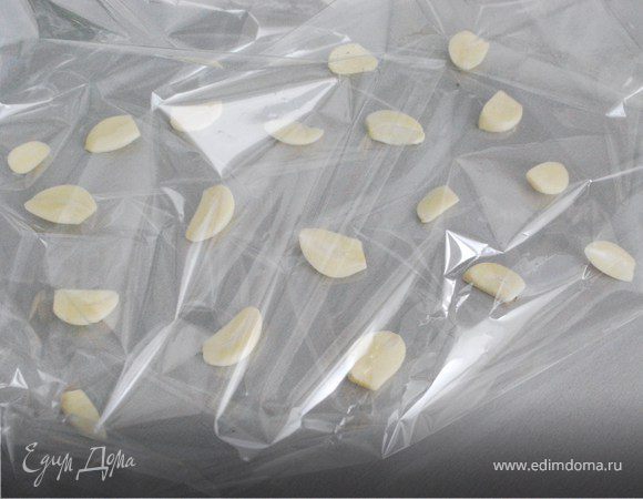 Чеснок почистите, нарежьте вдоль на 2–3 части и большую часть разложите в рукаве так, чтобы на него помещалось мясо (можно еще положить кружочки моркови).