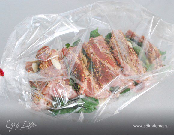 Вернемся к мясу. Оставшийся чеснок положите на мясо, между «страничками» разместите веточки кинзы и листики базилика. Сверху посыпьте зернами горчицы. Аккуратно положите мясо в рукав. Расправьте его, чтобы запеклось равномерно.