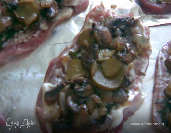 Грибы обжарить на сковороде,как только лишняя жидкость испарится добавить масло сливочное и мелко порезанный лук.Хорошо обжарить,добавить нарезанные кружочками солёные корнишоны. И выложить на мясо.