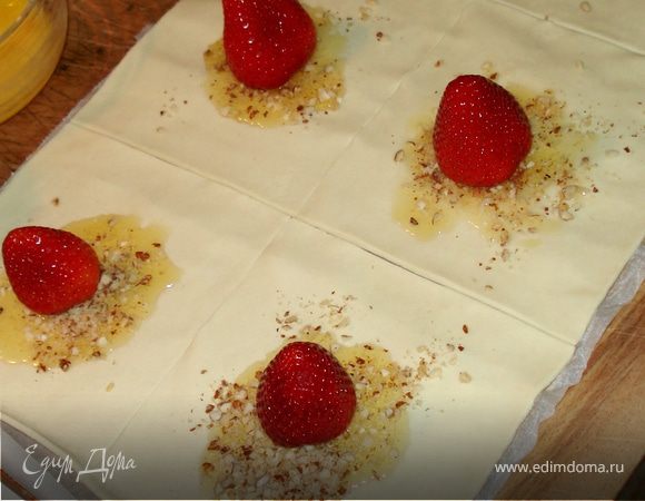 Разогреваем духовку до 180-200C Театсто раскатываем,разрезаем на квадраты.Центр каждого квадрата мажем жидким медом,посыпаем молотыми орехами.Сверху кладем клубнику.Орехи берете любые,у меня было немного грецких,лесных и миндаля.Я их все вместе смолола и в пирожные :) .Затем складываем тесто конвертиком,смазываем яйцом
и в духовку на 10 мин.