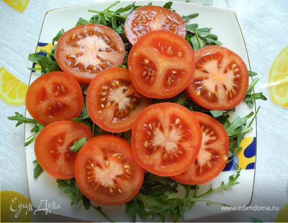 Руколу выложить на тарелку. Помидоры порезать кружками и положить на руколу.