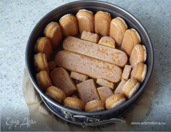 На дно разъемной формы (18-20см) кладем бумагу для запекания. Дно и стенки выкладываем печеньем. Для бортиков печенье разрезать напополам и размещать сахарной стороной наружу.