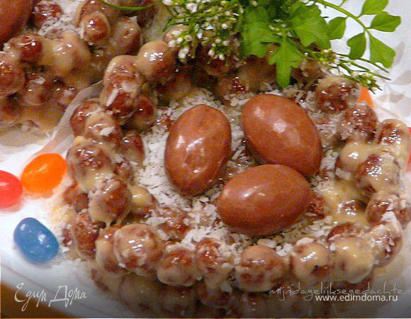 Растопить шоколад, масло, мед. Вмешать шарики и сформировать (терпеливо) гнезда, выкладывая на бумагу для выпечки. Остудить их в холодильнике и украсить мини конфетами-яичками.
Можно маленькие цветные перья положить еще